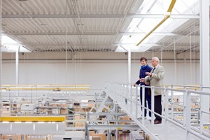 Two men standing on a bridge inside a factory