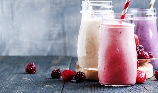 Three migraine-friendly fruit smoothies with a scattering of berries