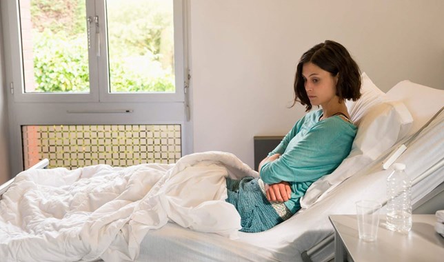 Young woman in hospital bed thinking about difficult health decisions 